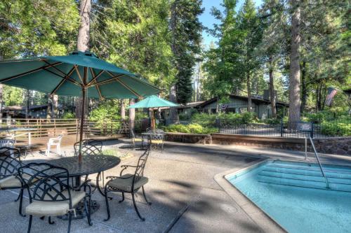 a table with an umbrella and chairs next to a pool at Waters Edge Escape - Patio with BBQ Near Beach in Tahoma