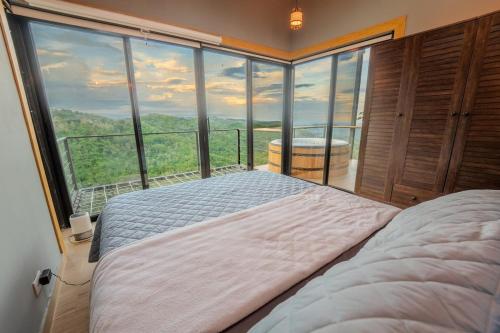 Un dormitorio con una cama frente a una gran ventana. en Dreamy cabin in Comasagua, La Libertad, en Comasagua