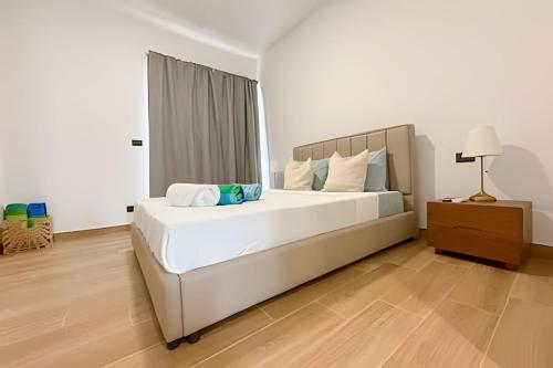 ein Schlafzimmer mit einem großen weißen Bett und einem Nachttisch in der Unterkunft Estudios en el corazón de Punta Cana in Punta Cana