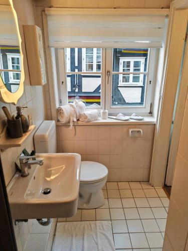 ein Badezimmer mit Toilette, Waschbecken und Fenster in der Unterkunft Café Pension in Celle