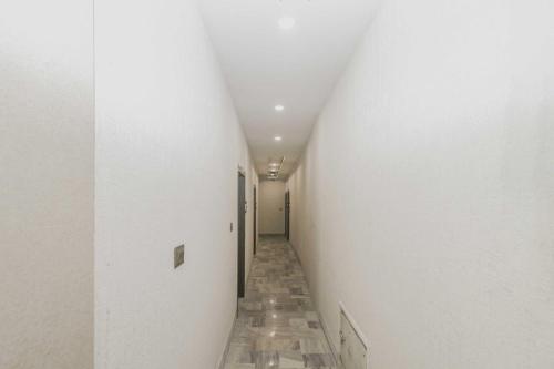 a long corridor with a white wall and a corridorngthngthngthngth at Hotel O Ranchi Station Road Near Gurudwara in Rānchī