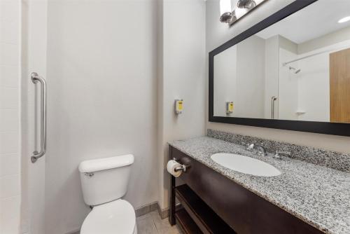 a bathroom with a toilet and a sink with a mirror at Best Western Plus Sand Bass Inn and Suites in Madill