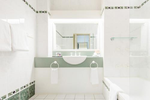 a white bathroom with a sink and a mirror at Mercure Charlestown in Newcastle