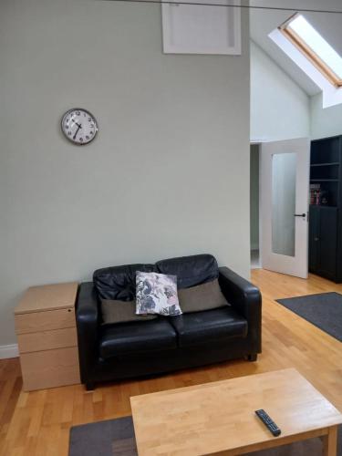 a black leather couch in a living room with a clock at Port Omna Ciúin in Portumna