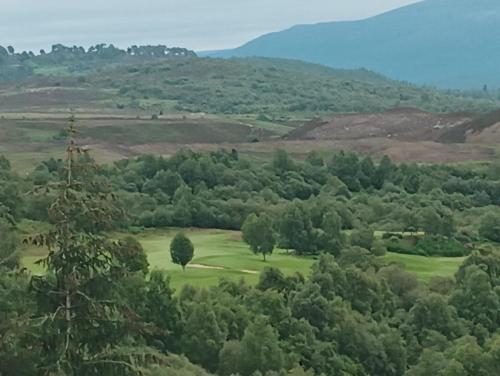a view of a golf course in the hills at Tom Liath Annexe in Kingussie