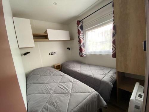 a small bedroom with two beds and a window at Mobil home Cap ferret les viviers siblu in Lège-Cap-Ferret