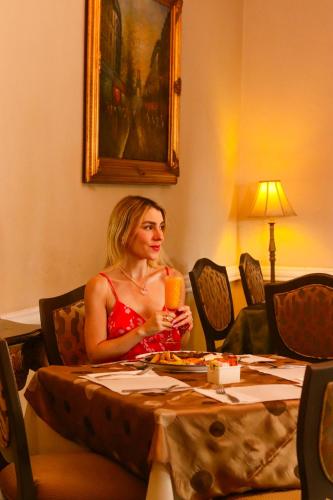 a woman sitting at a table with a glass of juice at Hacienda San Angel in Ensenada