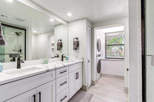 a white bathroom with two sinks and a window at Steps to Englewood Beach Home with Outdoor Oasis! in Englewood