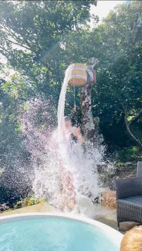 a boy jumping into a swimming pool with a water fountain at The Big Cwtch Shepherd's Hut in Kidwelly