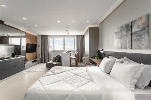 a bedroom with a large white bed and a kitchen at Studio 7 Ed. Milano_Bela Vista Mar in Florianópolis