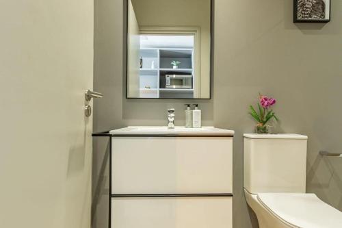 Un baño con lavabo, espejo e inodoro. en 1819 at one thibault apt, en Ciudad del Cabo