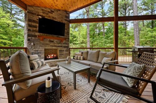 a screened in porch with a couch and a fireplace at Luxury Cabin- Sleeps 12- Hot Tub - Dog Friendly in Broken Bow
