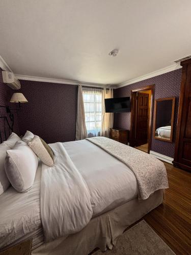 a bedroom with a large bed with white sheets at Hacienda San Angel in Ensenada