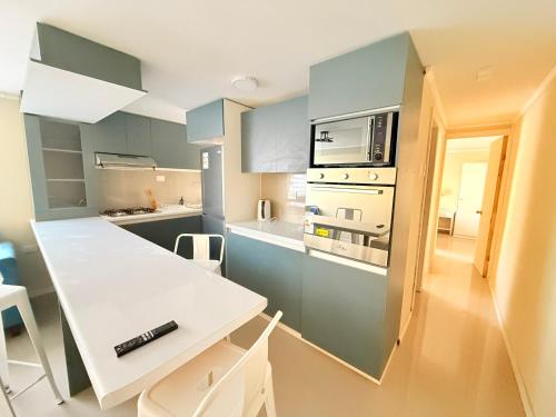 a kitchen with blue cabinets and a white table and chairs at Departamento primer piso a minutos de la playa in Constitución