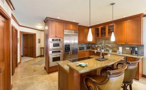 a kitchen with wooden cabinets and stainless steel appliances at Kolea 14F - Heated Pool Gym & More in Waikoloa
