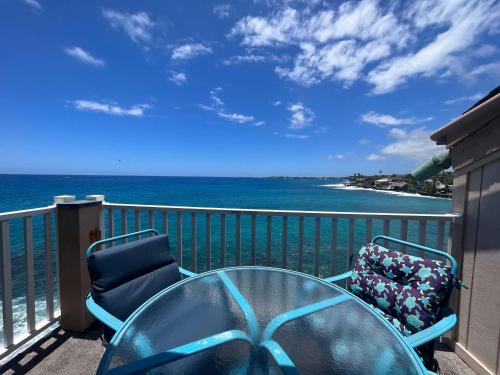 a balcony with a table and chairs and the ocean at Oceanfront Vintage Retreat in Kailua-Kona in Kailua-Kona