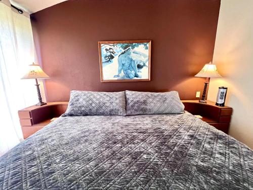 a bedroom with a bed and two lamps and a painting at Kona Isle Oceanfront Condo in Kailua-Kona