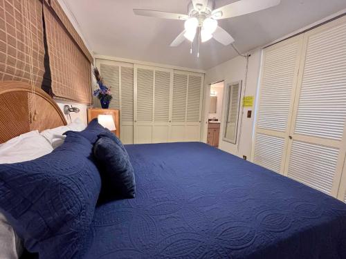 a bedroom with a blue bed with a ceiling fan at Kona Mansions - Ocean Views & Amenities in Kailua-Kona