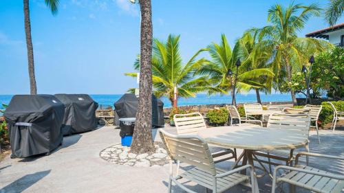 a table and chairs on a patio near the beach at Casa De Emdeko Condo with Pool AC & Ocean Views in Kailua-Kona