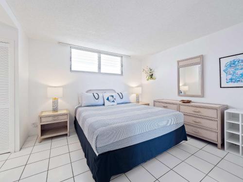a white bedroom with a bed and a mirror at Kolu Honu - Stunning Beachfront Condo for 2 in Kailua-Kona