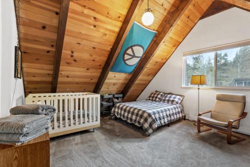 a crib and chair in a room with wooden ceilings at Christmas Valley Chalet - Tahoe Adventure Awaits in South Lake Tahoe