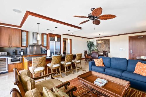 a living room with a blue couch and a kitchen at Panoramic Ocean Views in Ko Olina in Kapolei