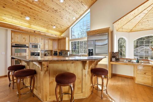 a kitchen with wooden cabinets and a large island with bar stools at The Lodge on Oaxaco - Epic Man Cave with Billiard Room in South Lake Tahoe
