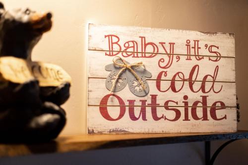Un cartel que dice "Bebé, hace frío afuera" en un estante. en Come Snuggle Up at Cozy Bear Cabin, en South Lake Tahoe