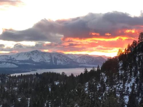 a sunset over a lake with snow covered mountains at Heaven's Nest - the BEST views of Lake Tahoe in Stateline