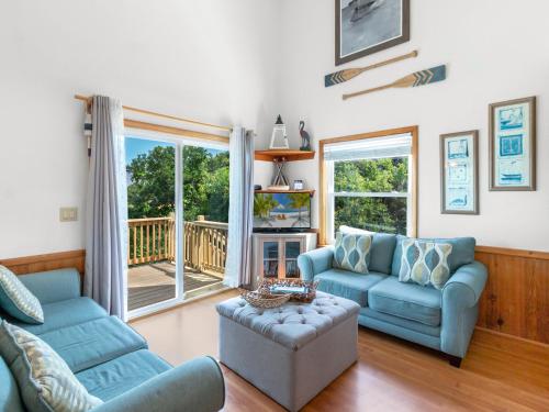 a living room with blue furniture and a balcony at 2130 - Luna Blu Cottage in Sea Hawk