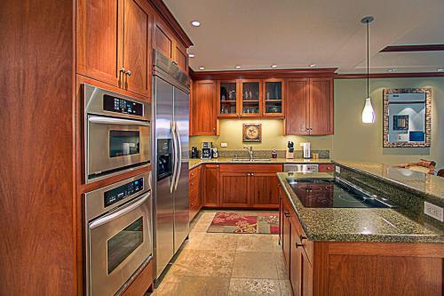 a kitchen with wooden cabinets and stainless steel appliances at Kolea 11D - Walk to the Beach in Waikoloa