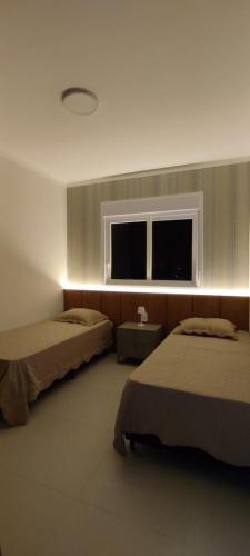 a room with two beds and a window at Mirante da barra in Tramandaí