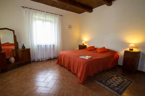 a bedroom with a bed with orange sheets and a window at Casale Coccinella in Preci