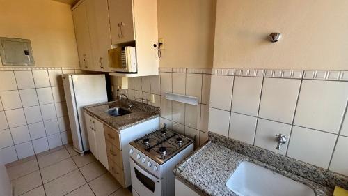 a small kitchen with a stove and a refrigerator at Apartamentos Thermas do Bandeirante in Caldas Novas