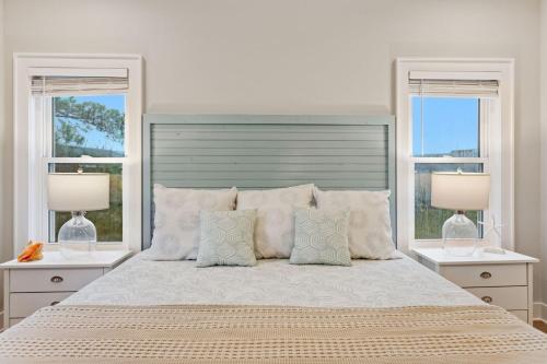 a bedroom with a large bed with two windows at 5046 - Pelican Palm in Kill Devil Hills