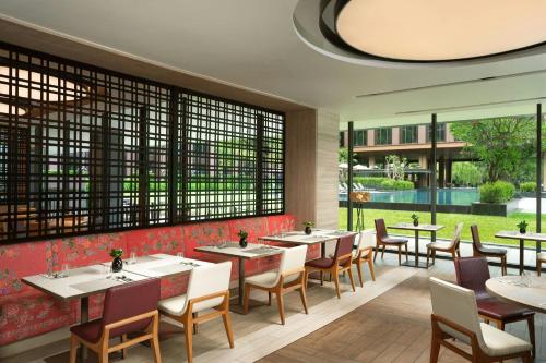 a restaurant with tables and chairs and a large window at Courtyard by Marriott Bangkok Suvarnabhumi Airport in Lat Krabang