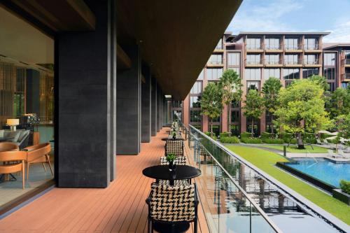 a balcony with tables and chairs and a pool at Courtyard by Marriott Bangkok Suvarnabhumi Airport in Lat Krabang