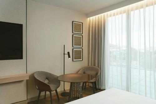 a room with a table and chairs and a television at Courtyard by Marriott Bangkok Suvarnabhumi Airport in Lat Krabang