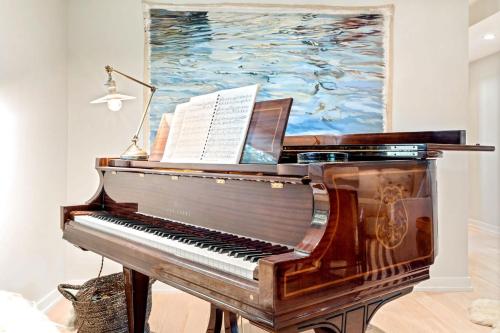 a piano in a living room with a painting at Kayaks & Sup's - Private Dock - Grand Piano in Kittery