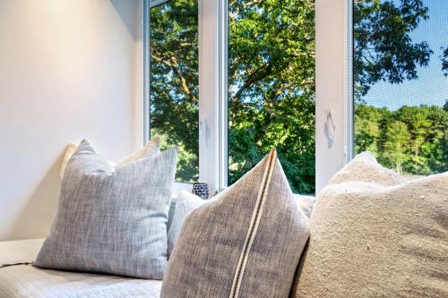 a group of pillows sitting on a couch in front of a window at Kayaks & Sup's - Private Dock - Grand Piano in Kittery