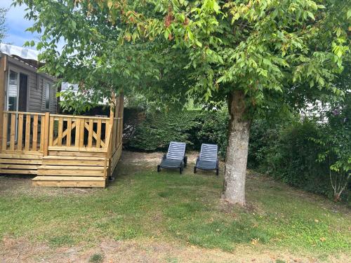 two chairs sitting under a tree next to a house at Mobil home 6 personnes in Les Mathes