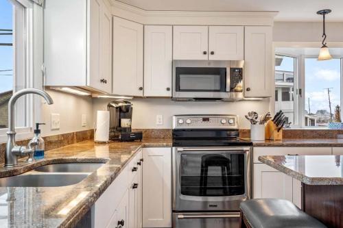 eine Küche mit weißen Schränken und einer Spüle und einer Mikrowelle in der Unterkunft Oceanfront - Front Porch - Back Deck - Kitchen in Wells