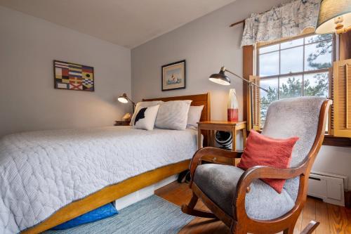 a bedroom with a bed and a chair and a window at Beachfront and only 30 Steps To Beach in Saco