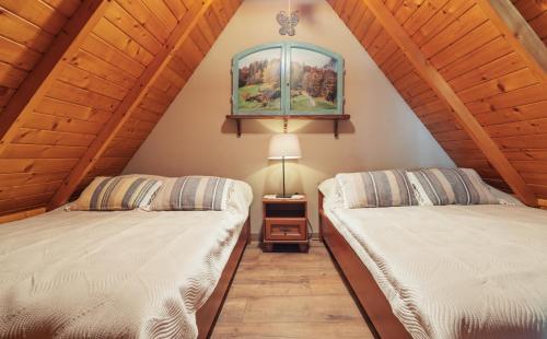 two beds in a room with wooden ceilings at Willa pod Jemiołą in Wisła