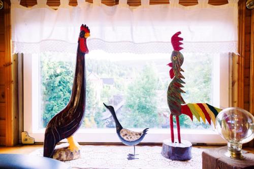 three wooden statues of chickens in front of a window at Willa pod Jemiołą in Wisła