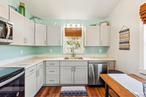 a kitchen with white cabinets and a sink at 5047 - Sandy Cove OBX in Kill Devil Hills