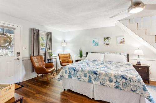 a bedroom with a bed and two chairs at 5047 - Sandy Cove OBX in Kill Devil Hills