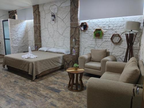 a bedroom with a bed and a couch and a chair at Hotel Spa el Gran Coral in San Juan Cosalá