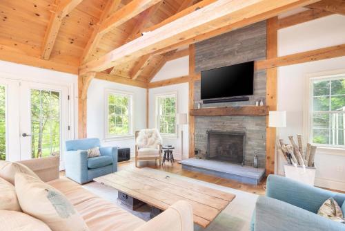 a living room with a fireplace and a tv at Summerset Villa by Rove - Family Home with Pool & Hot Tub in Bridgehampton