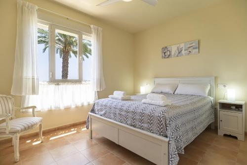 ein Schlafzimmer mit einem Bett und einem Fenster mit einer Palme in der Unterkunft Brisa del Valle Casa con Jardín Piscina Parking in Vera